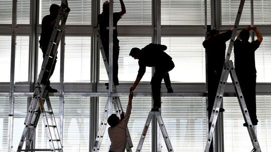 Silhouetten von Arbeitern, die eine Bühne abbauen