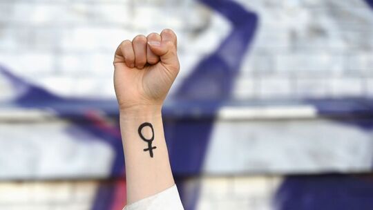 Eine Frau hebt ihre Faust mit Venussymbol die Höhe