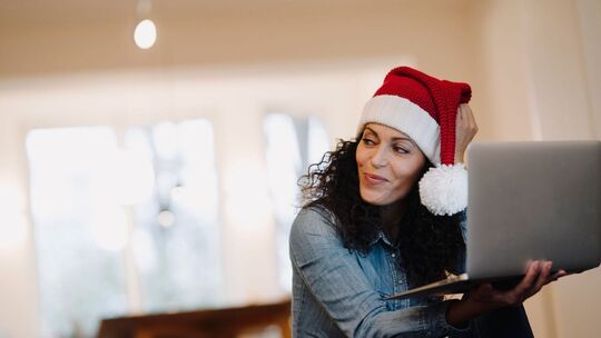 Eine Frau mit Weihnachtsmütze am Laptop