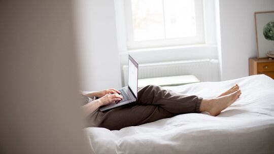 Eine Frau sitzt mit Laptop im Bett Eine Frau sitzt mit Laptop im Bett
