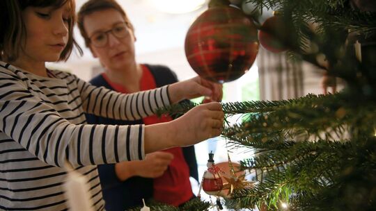 Mutter und Tochter schmücken gemeinsam den Weihnachtsbaum