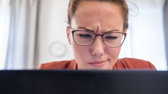 Eine junge Frau blickt skeptisch auf ihren Laptop Eine junge Frau blickt skeptisch auf ihren Laptop