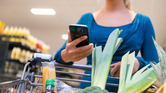 Eine Frau mit Smartphone im Supermarkt Eine Frau mit Smartphone im Supermarkt
