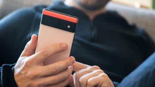 Ein Mann hält ein Google Pixel 6 in den Händen Ein Mann hält ein Google Pixel 6 in den Händen