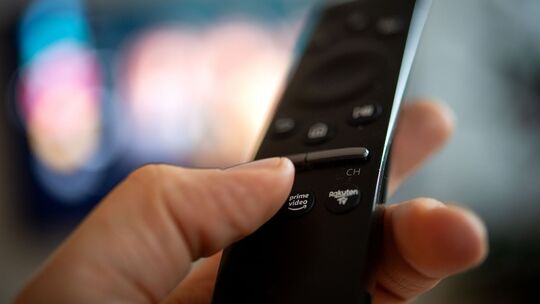 Ein Mann hält eine Fernbedienung mit der Aufschrift Amazon Prime