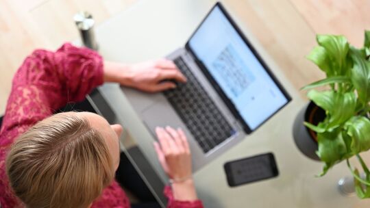 Eine Frau sitzt zuhause an einem Laptop