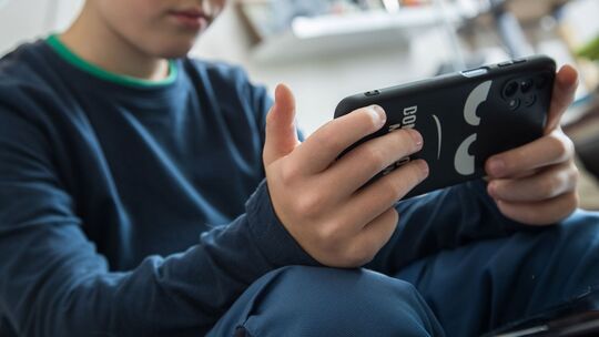 Ein Junge schaut auf sein Smartphone Ein Junge schaut auf sein Smartphone