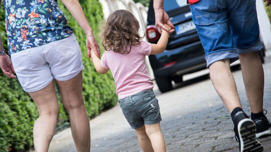 Ein kleines Mädchen an den Händen von den Großeltern