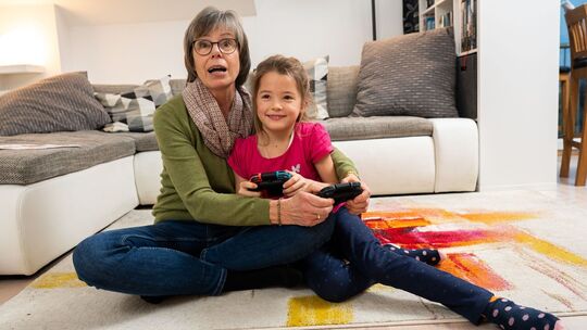 Oma spielt mit ihrer Enkelin an der Konsole