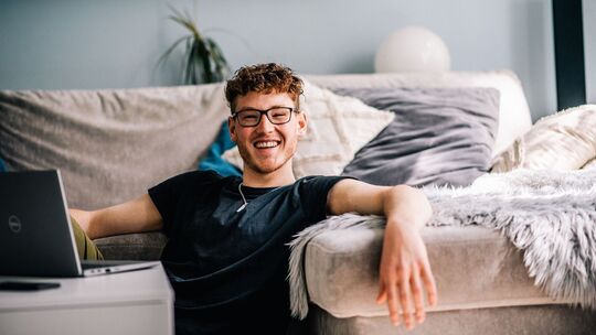 Ein Jugendlicher sitzt im Wohnzimmer vor einem Laptop