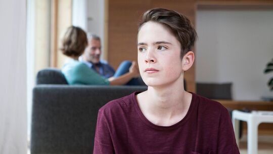 Jugendlicher sitzt genervt in einem Wohnzimmer