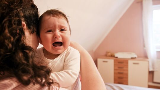 Eine junge Frau tröstet ihr weinendes Baby