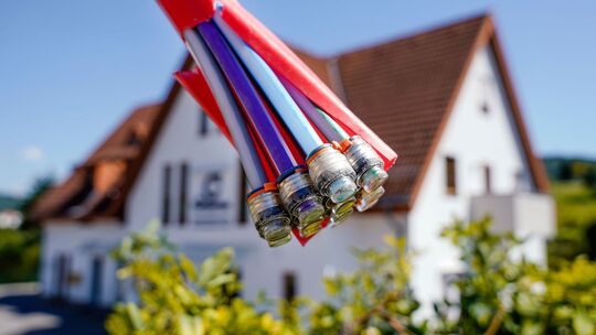 Bündel mit Umhüllungen für Glasfaserkabel vor einem Wohnhaus