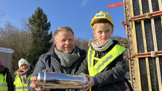 Große Freude in Dahlheim: Piet aus der Kita Zwergenhaus durfte mit Ortsbürgermeister Marco Jost die Zeitkapsel befüllen und in d