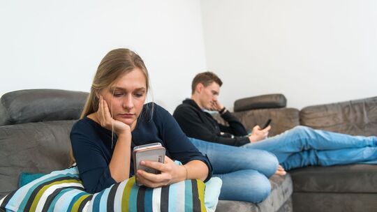 Ein Paar sitzt auf einem Sofa voneinander abgewandt