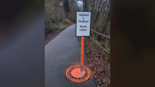 montiertes Schild auf Gullydeckel