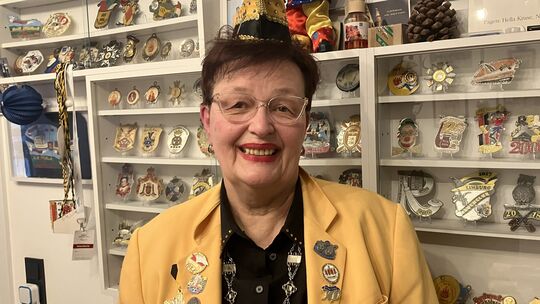 Eine Wand voller Erinnerungen: Christine Vogt-Hehl posiert vor den Vitrinen mit den zahlreichen Karnevalsorden, die sie im Laufe