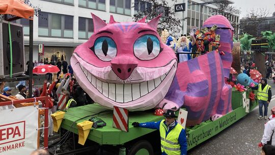 Die Grinsekatze aus Alice im Wunderland setzt beim Rosenmontagszug auf dem Wagen der SV 08 Hillscheid sein verrücktestes Grinsen