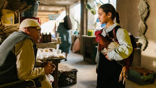 Lamia (Baneen Ahmed Nayyef) ist mit ihrem Hahn Hindi auf dem Markt unterwegs, um die benötigten Lebensmittel für einen "Kuchen f