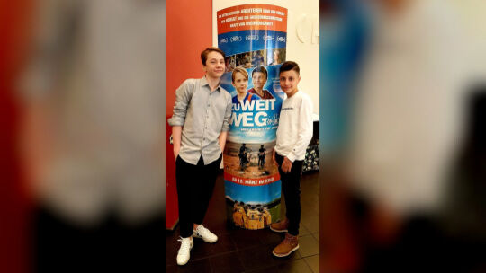 Die Schauspieler Yoran Leicher und Sobhi Awad posieren vor dem Filmplakat von "Zu weit weg".