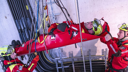 Das fiktive Unfallopfer Patrick Henschel liegt noch angeschnallt waagerecht in der Rollup-Trage. Tobias Hisgen (links) und Flori