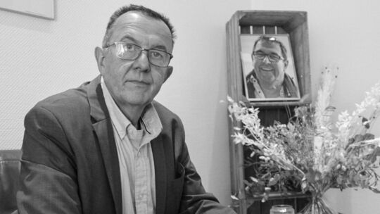 Christian Berentzen sitzt im Mai 2023 im Foyer des Rhenser-Zentrale, neben ihm ein Porträtbild seines Bruders. Friedrich Berentz