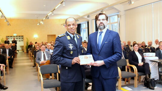 Oberst Samuel Mbassa (links), Kommodore des Taktischen Luftwaffengeschwaders 33, schenkt Gastredner Frank Sauer die Commander's