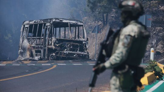 Ein Soldat steht in Cointzio neben einem ausgebrannten Bus Ein Soldat steht in Cointzio neben einem ausgebrannten Bus