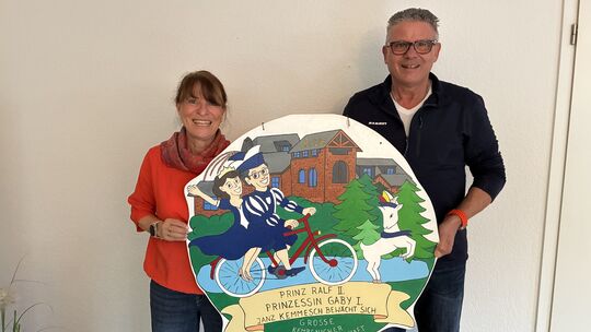 Das Kempenicher Prinzenpaar Gaby Grohs-Herrmann und Ralf Herrmann hält die handgemalte Originalgrafik ihres Karnevalsordens von