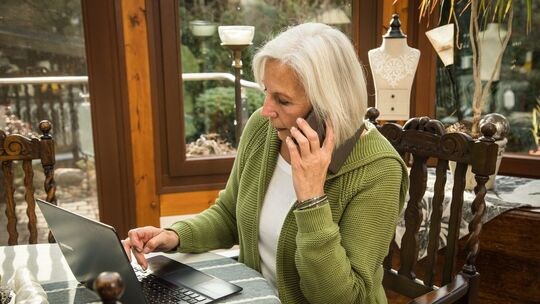 Seniorin mit Smartphone und Laptop