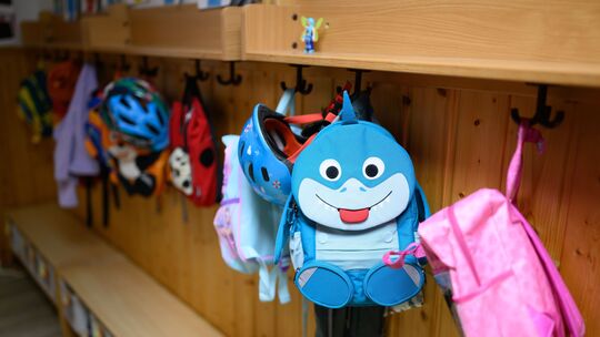 Kinderrucksäcke hängen in der Garderobe einer Kita.