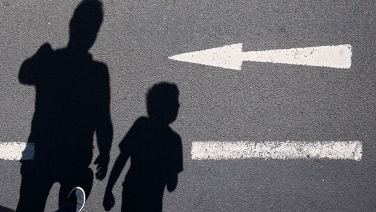 Schatten von einem Mann und einem Kind sind auf einer Straße