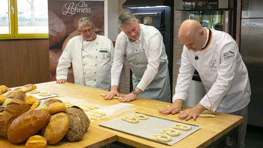 Ran an den Teig: CDU-Spitzenkandidat Gordon Schnieder formt mit Lohner-Geschäftsführer Bernd Kütscher (rechts) und Firmengründer