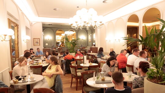 Zahlreiche Gäste sitzen im mittleren Bereich des Cafés Baumann.