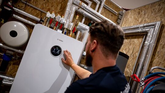 Handwerker zeigt an einer Wärmepumpe auf die Anzeige