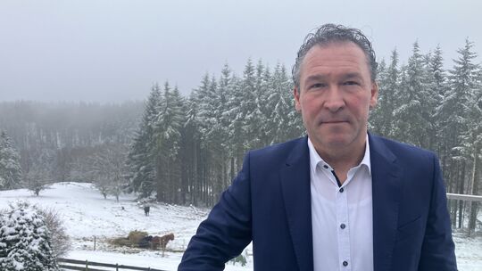 Christian Müller steht vor winterlicher Kulisse auf seiner Terrasse in seinem Heimatort Langenfeld. Im Hintergrund sieht man sei