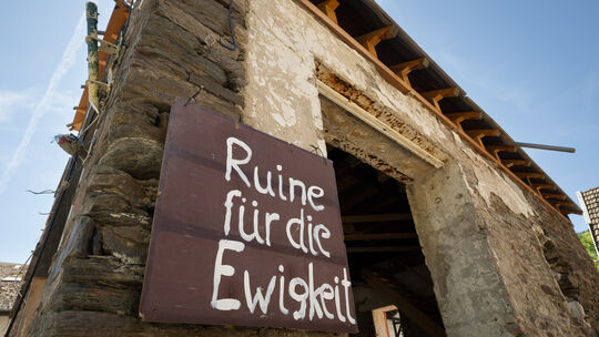 „Ruine für die Ewigkeit“ steht auf einem Schild an einem zerstörten Haus im Weinort Mayschoß. Wie kann man den Wiederaufbau vora
