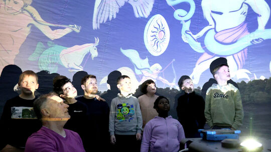 Klaus Völkel erklärt den Erstklässlern in seinem mobilen Planetarium den Weltraum.