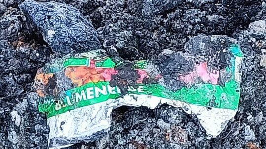 Reste von Verpackungen sind zwischen den Ascheresten zu erkennen. Auch das wurde hier abgelagert.