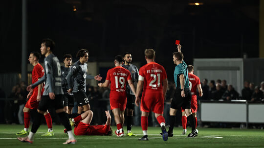 Schiedsrichter Jan-Hagen Engel zeigt hier Rot-Weiss-Akteur Giulio Multari (in Grau-Schwarz, Erster von rechts) in Bitburg die Ro