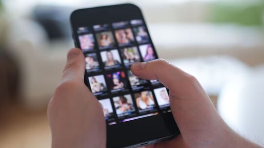 Mann schaut sich Videos auf einem Smartphone an