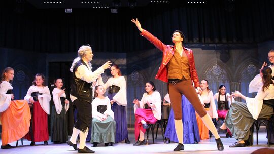 Carolin Hoffmann mimt den garstigen Gaston, Lile Zastrow steht in der Rolle von Belles Vater auf der Bühne. Im Hintergrund ist d