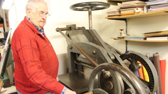 Hier betätigt Walter Fries "Frau Krause", die wuchtige Prägepresse, die mehr als 100 Jahre auf dem Buckel hat und noch immer ihr