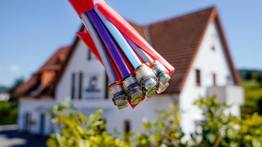 Bündel mit Umhüllungen für Glasfaserkabel vor einem Wohnhaus