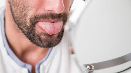 Mann betrachtet seine Zunge im Spiegel Mann betrachtet seine Zunge im Spiegel