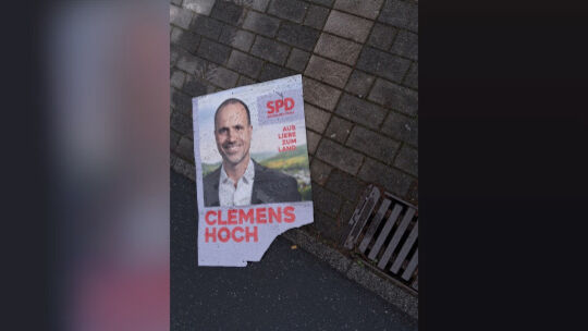 Ein Plakat von Clemens Hoch (SPD) liegt in der Gosse – gesehen in Mendig.
