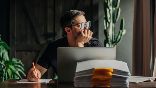 Ein Mann arbeitet am Laptop und sieht aus dem Fenster Ein Mann arbeitet am Laptop und sieht aus dem Fenster