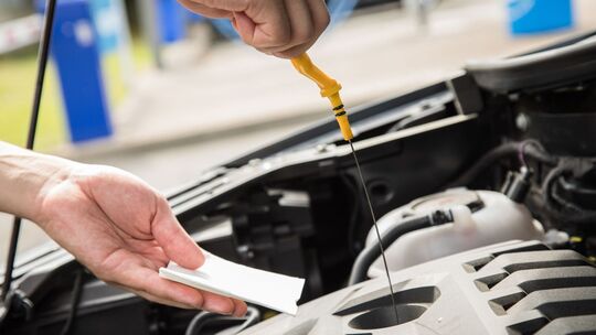 Ein Mann prüft den Ölstand seines Autos Ein Mann prüft den Ölstand seines Autos