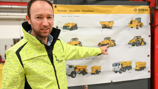 Anel Zolj ist Werkleiter am Hauptsitz der Bomag in Boppard. Auf einem Plakat sind die Maschinen der Recycler-Sparte zu sehen, di