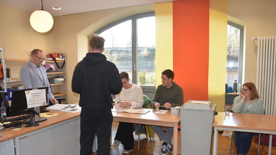 Eine Szene vom sonnigen Sonntag: Ein Wähler gibt seine Wahlbenachrichtigung ab und erhält den Wahlschein. Wie er haben es auch T